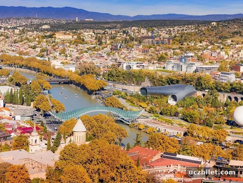 Tiflis, Gürcistan'ın sonbahar aylarında Kura nehri ve Rike Parkı'nı mavi bir gökyüzü altında gösteren panoramik manzara